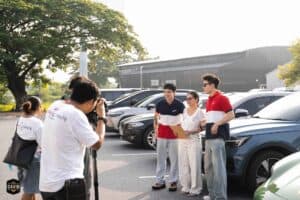 A TV production crew filming hosts in the expansive outdoor parking area of Davin Cafe, utilizing the location as an event space rental in Bangkok.